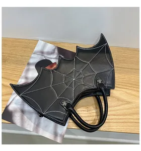 Detailed view of bat-shaped bag with white spider web stitching and cross studs