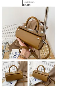 Detail of khaki cylindrical PU leather bag with silver lock and adjustable shoulder strap