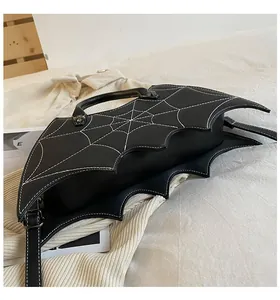 Close-up of bat-shaped gothic handbag with white spider web stitching and star rivets