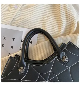 Close-up of spider web stitching and silver cross metal hardware on black leather tote