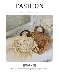 Detail of semi-circular straw bags with wooden handles and raffia fringe in boho style