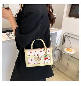Detail of printed crossbody bag with cherry pattern and golden flower twist lock clasp