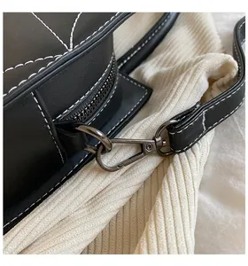 Detail of black leather bag featuring white contrast stitching and dark metal zipper hook
