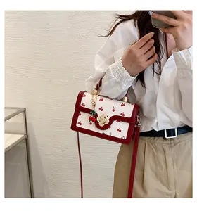 Detailed view of cherry print crossbody bag with gold flower clasp and cherry charm