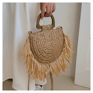 Close-up of bohemian straw tote bag featuring long fringes and round wooden handles