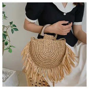 Detail of bohemian straw handbag featuring a semi-circle design with long raffia tassels