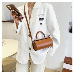 Brown cylindrical PU leather bag shown with shoulder strap and matching mobile case