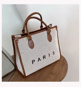 Detail of canvas tote bag with brown leather trim and PARIS print on wooden stool