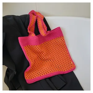 Close-up of orange and pink hand-knitted tote bag featuring hollow mesh and wavy straps