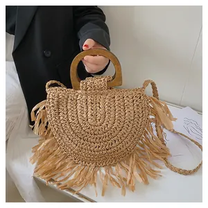 Detail of bohemian woven straw handbag featuring fringe edges and round wooden handles