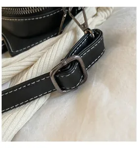 Close-up of black PU leather strap with white stitching and grey metal buckle detail