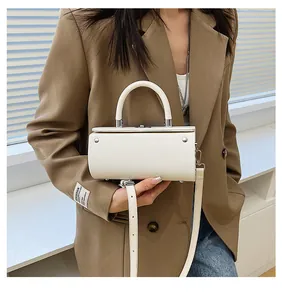 Detail of white cylindrical handbag with silver hardware and adjustable shoulder strap