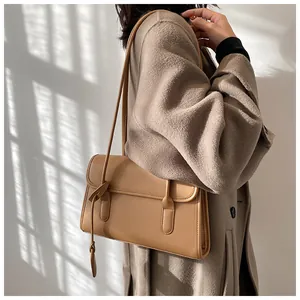 Side view of a light brown faux leather shoulder bag with decorative leather knot details