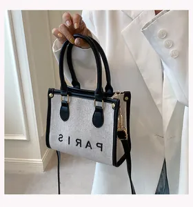 Detail of canvas tote bag with black leather trim, Paris embroidery and shoulder strap