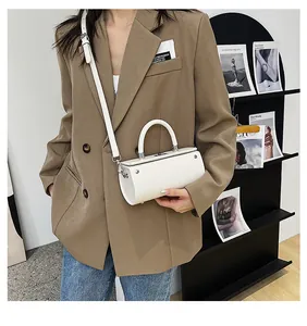 Lifestyle shot of a white minimalist cylindrical crossbody bag styled with an oversized blazer