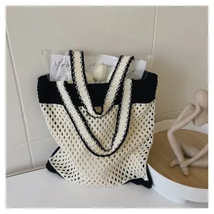 Detail of a minimalist black and white knit tote bag with a chic hollow mesh design