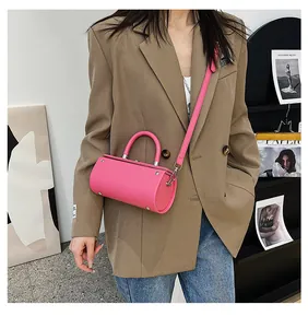 Hot pink cylindrical handbag shown on model with shoulder strap and metal rivets