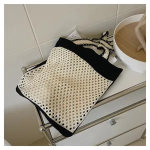 Detail shot of a black and white hand-woven knit tote bag with mesh texture and large capacity