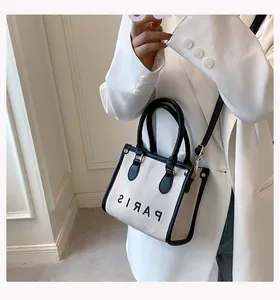 Detailed view of canvas tote bag with leather trim and Paris print on a white blazer