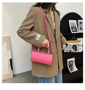 Street style shot of a bright pink cylinder handbag with silver studs and top handle