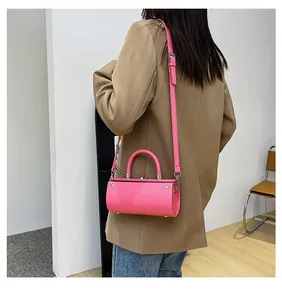Hot pink cylindrical mini handbag shown on shoulder with stylish khaki suit outfit