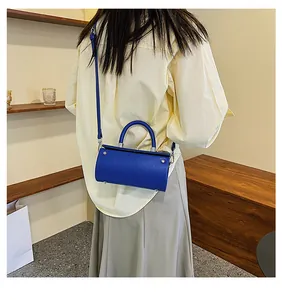 Close-up of royal blue cylindrical handbag with smooth leather texture and metallic hardware