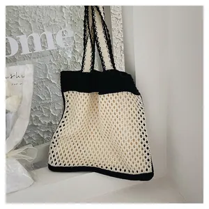 Detail of hand-knit hollow mesh tote bag with black and white striped shoulder straps