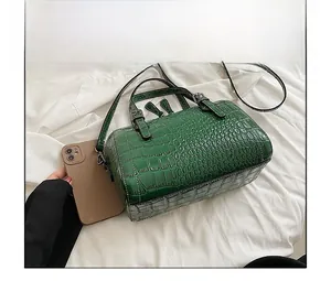 Green crocodile pattern handbag shown with a smartphone for size comparison display