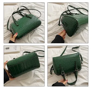 Detail view of dark green crocodile texture handbag with adjustable strap and handles