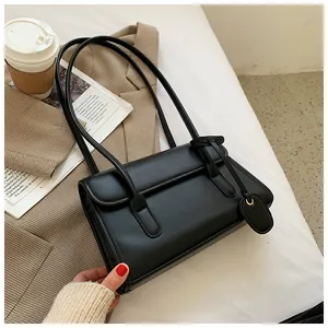 Flat lay of a vintage black leather underarm bag with a brown blazer and newspaper