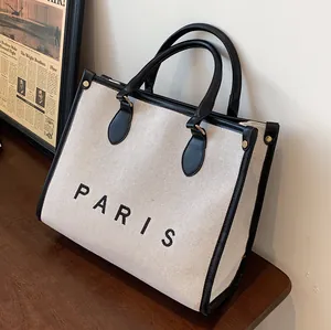 Large capacity canvas tote bag with black leather trim and Paris print on wooden table