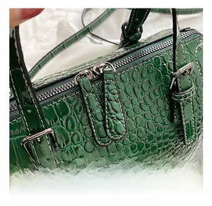 Detailed close-up of dark green faux crocodile leather handbag with silver metal zippers