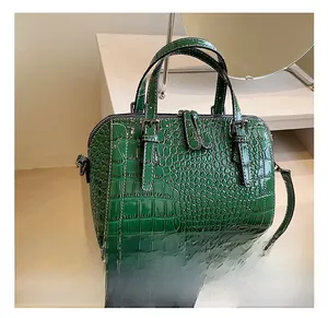 Close-up of crocodile pattern leather texture and white contrast stitching on green handbag