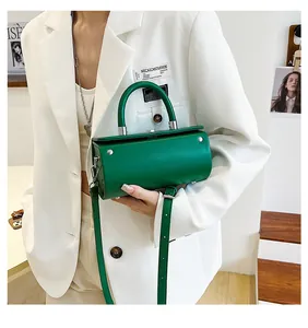 Detail of bright green cylinder handbag showing refined leather texture and metal buckles