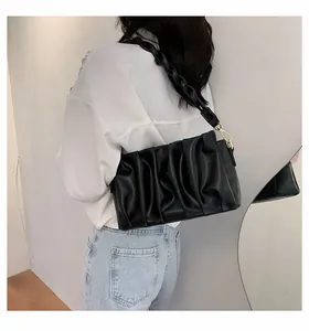 Detail of black pleated PU leather crossbody bag with a thick woven shoulder strap
