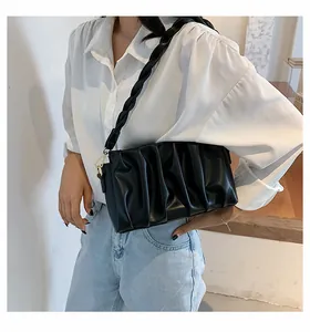Close-up of black pleated shoulder bag with unique twisted rope strap and gold metal rings