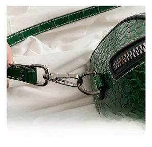 Macro detail of dark green crocodile texture bag with gunmetal swivel hook and zipper