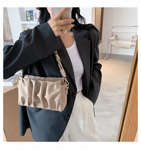 Close-up of beige pleated shoulder bag with twisted strap and gold hardware accents