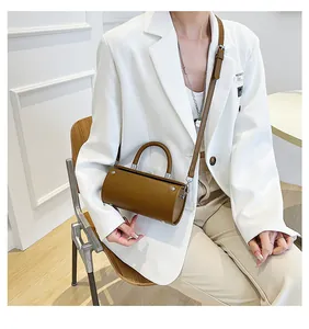 Brown leather cylinder bag styled with a white blazer for a minimalist fashion look