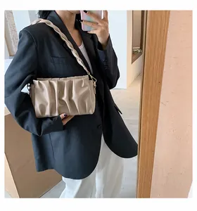 Detail of beige pleated cloud bag showing woven shoulder strap and metal buckle hardware