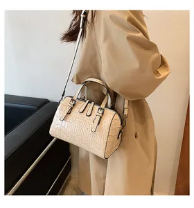 Detail of beige crocodile embossed Boston bag with double handles and shoulder strap