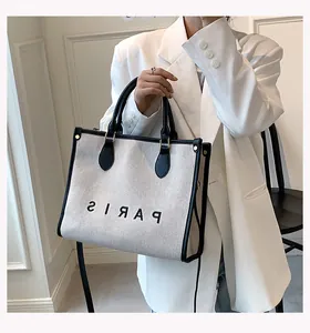 Detail of canvas tote bag with black leather trim and Paris print on a model