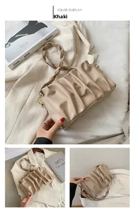 Detail of khaki pleated cloud bag with braided strap and golden hardware accents