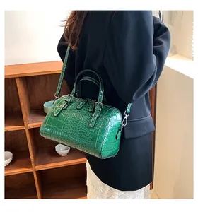 Detail of dark green crocodile pattern handbag with glossy finish and top handles