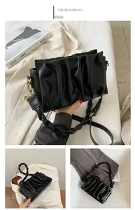 Detail of black pleated crossbody bag with woven handle and gold-tone metal hardware