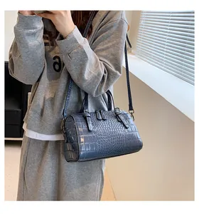 Close-up of blue crocodile pattern shoulder bag with top handles and adjustable strap