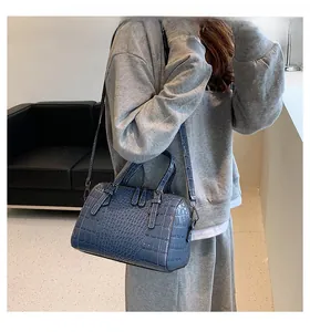 Detail of blue crocodile pattern boston bag showing texture and shoulder strap on model