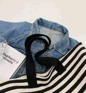 Close-up of reinforced stitching on black canvas handles of striped tote bag