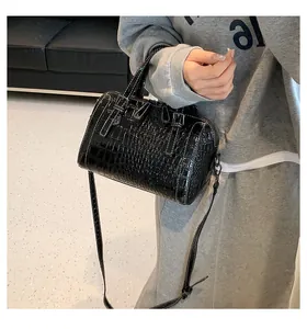 Detail of black crocodile texture handbag with adjustable strap and decorative stitching