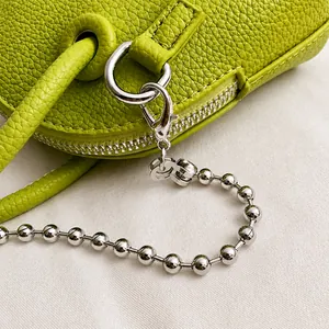 Detailed close-up of green pebble leather bag with silver metal chain and lobster clasp